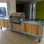 Aussenküche Iron Lärche Dielen mit Napoleon Gasgrill Bilex 485, 4er Gas-Kochfeld von AEG, Edelstahl Arbeitsplatte, Spühle mit Federbrause Mischbatterie, 5 Liter Boiler, 50 Liter Kühlschrank und Platz für 12 kg und 5 kg Gasflasche